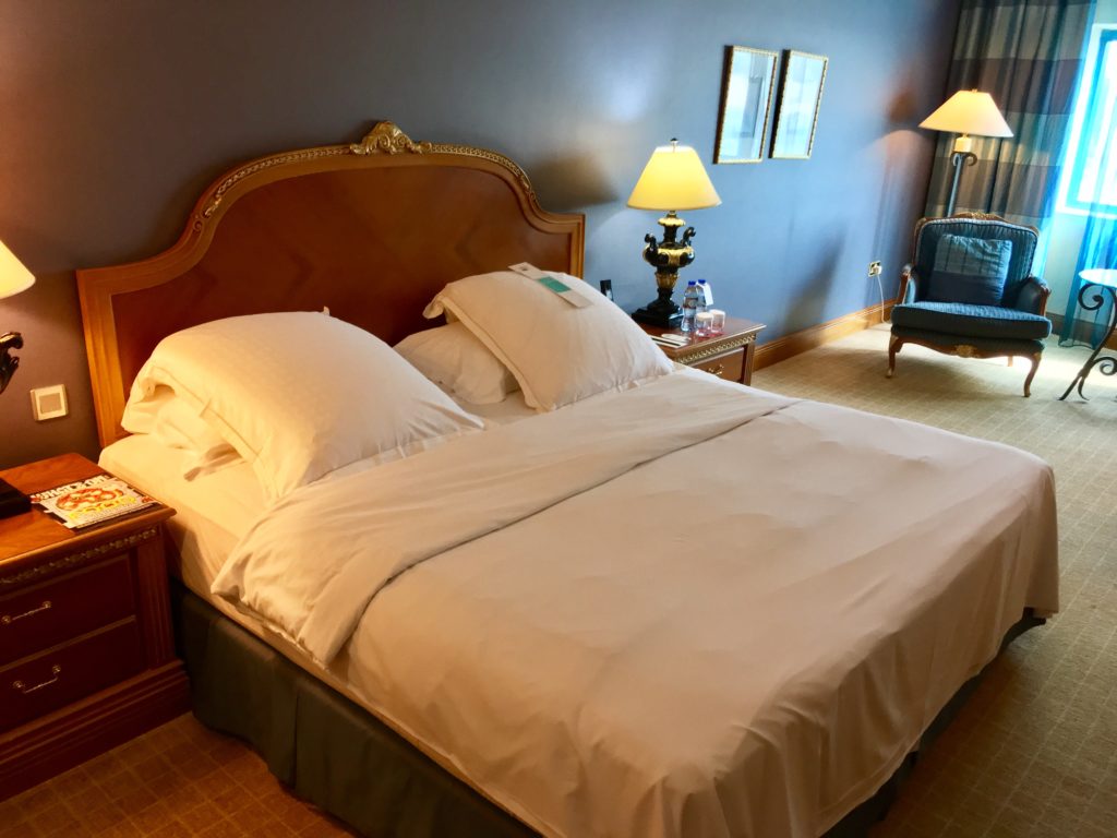 a bed with white sheets and pillows in a room