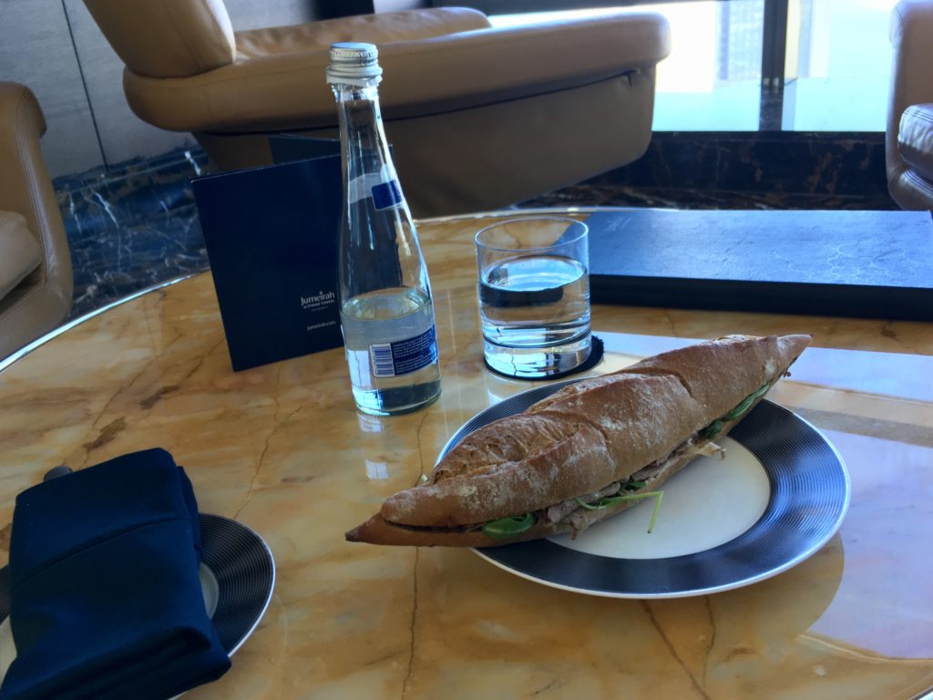 a sandwich on a plate and two water bottles on a table