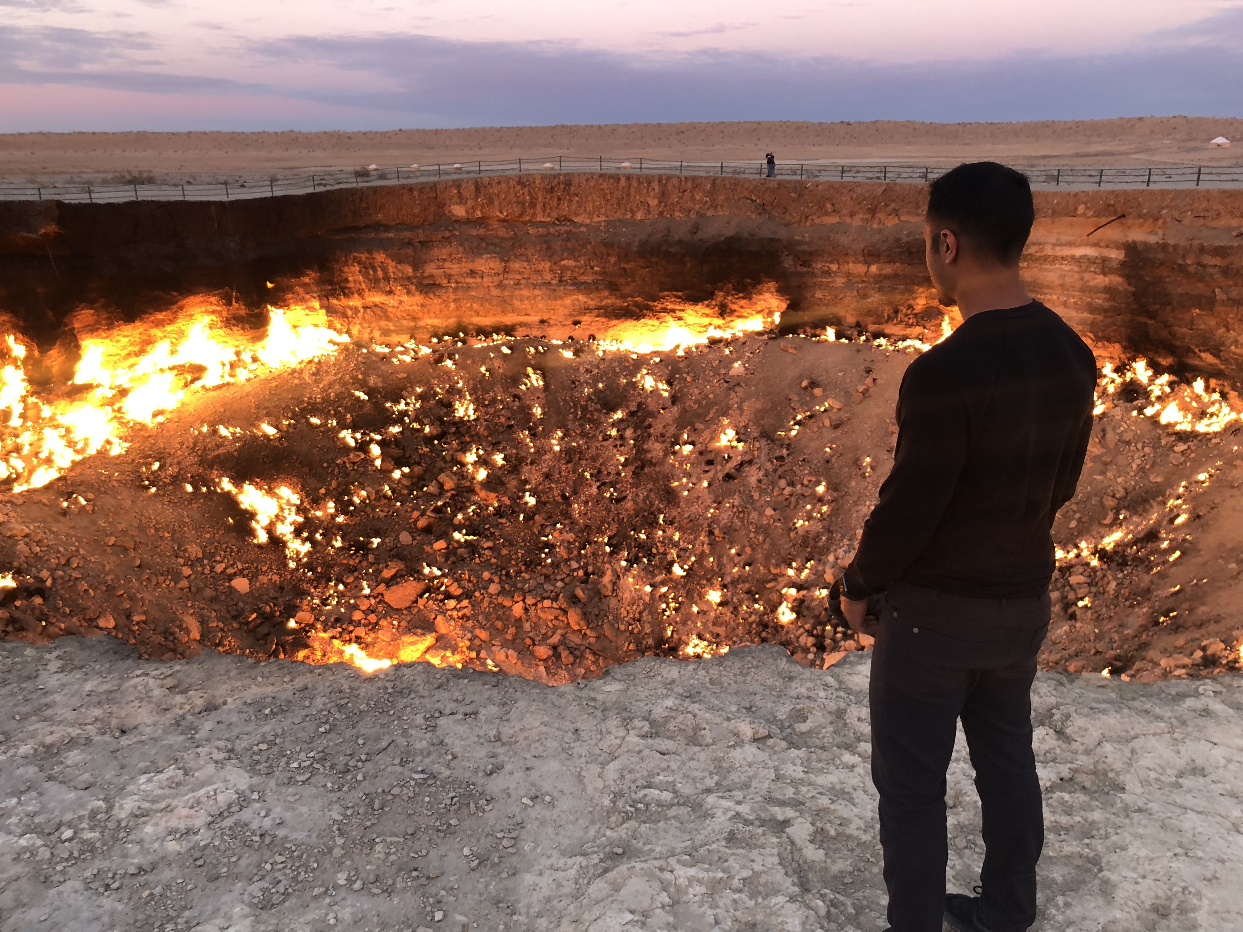 a man standing in front of a large hole with a fire in the background