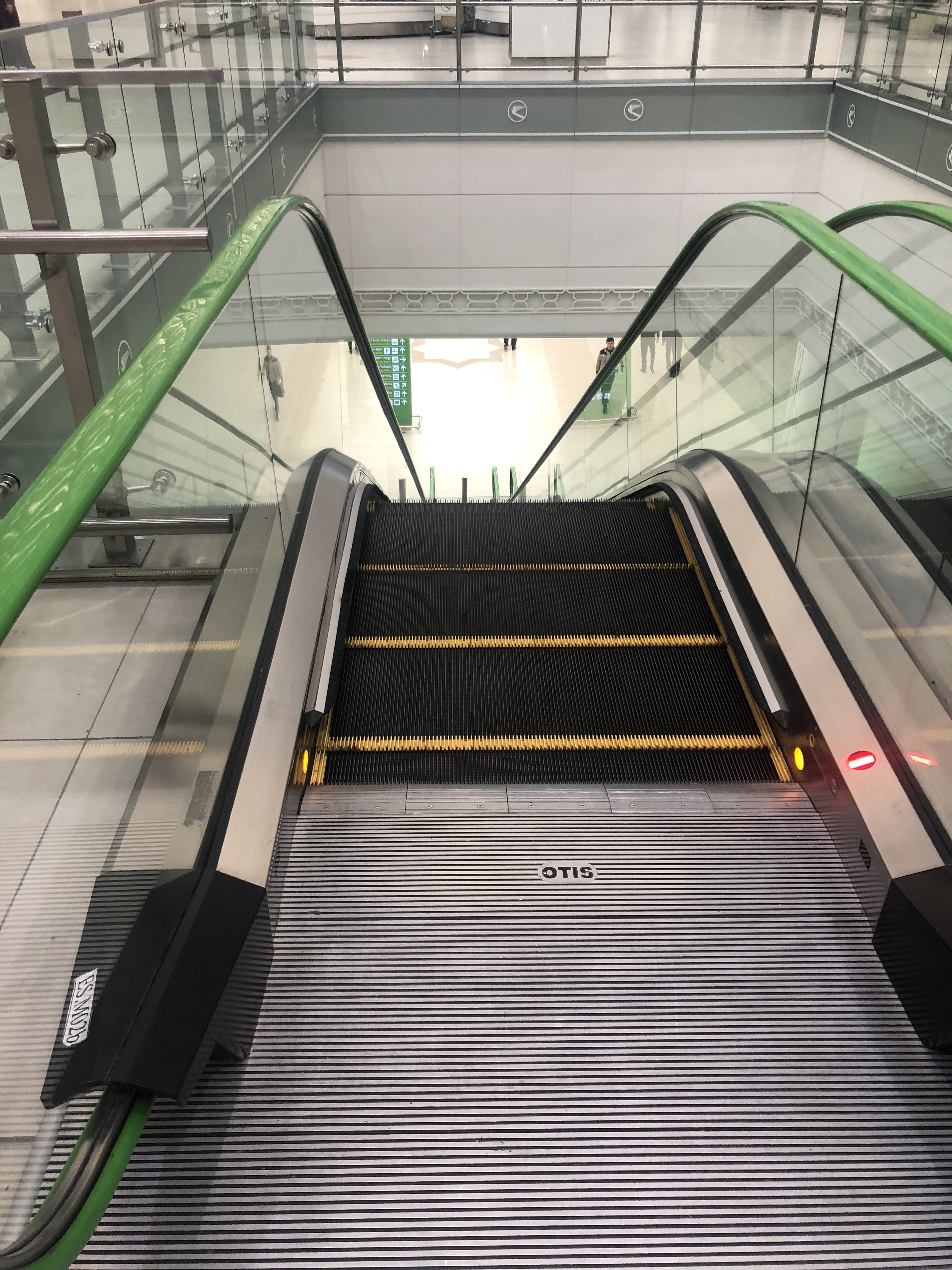 an escalator with a green railing