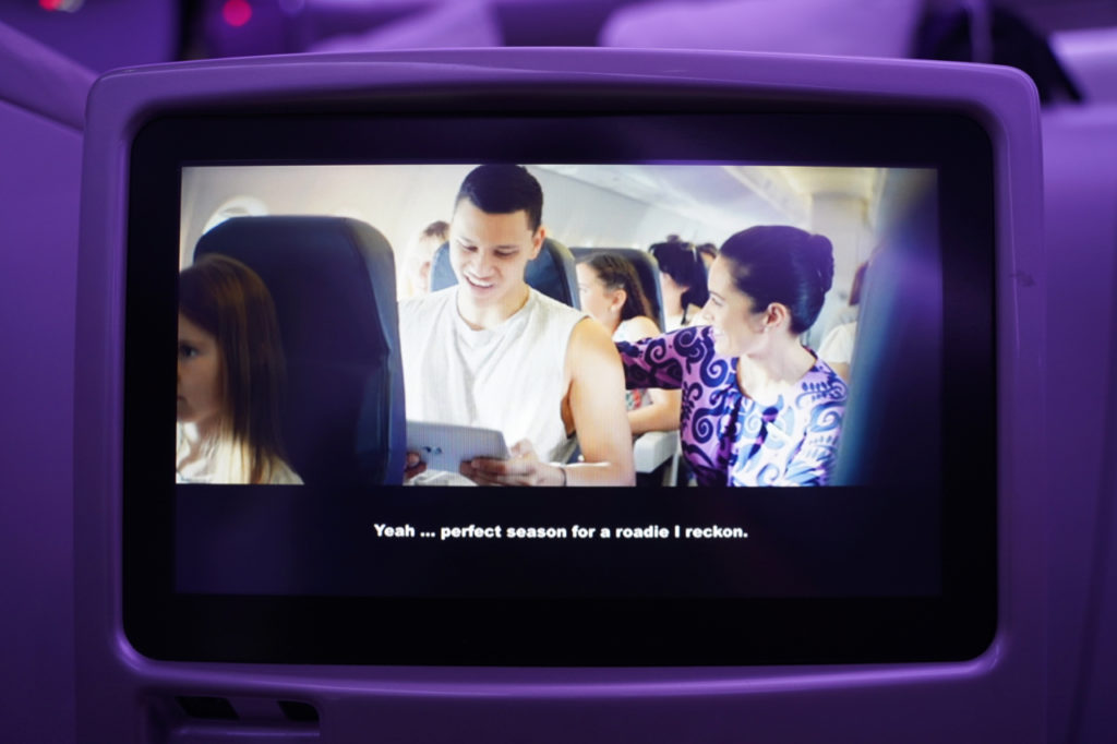 a screen with a screen showing people sitting in the seat of an airplane