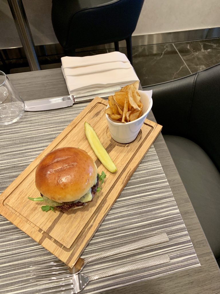 a burger and potato chips on a wooden tray