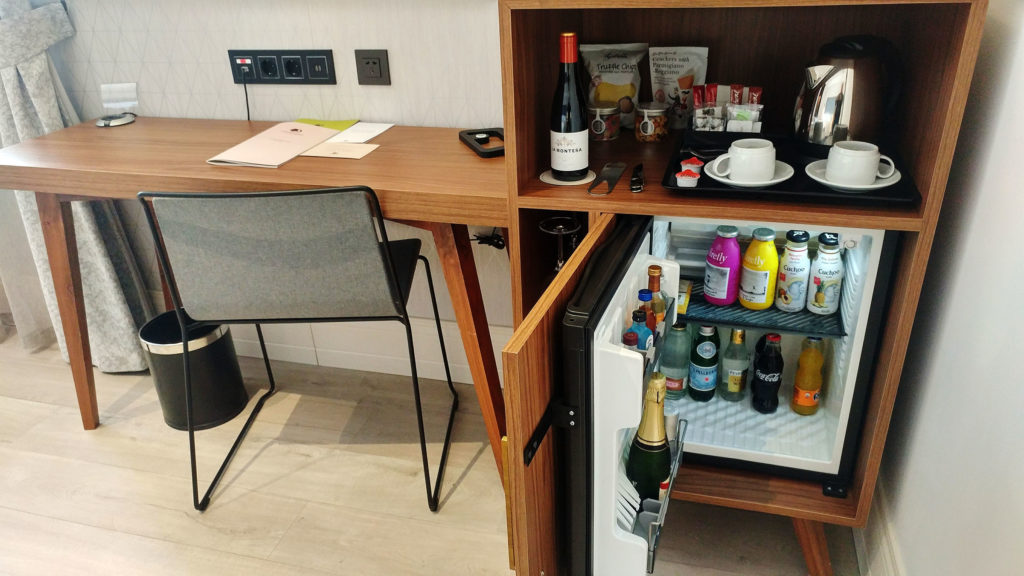 a small refrigerator with drinks and a chair in front of it
