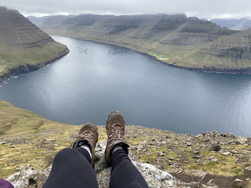 a person's legs on a cliff above a body of water