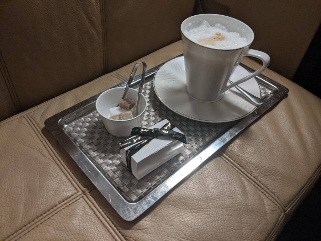 a cup of coffee and a small bowl of sugar on a tray