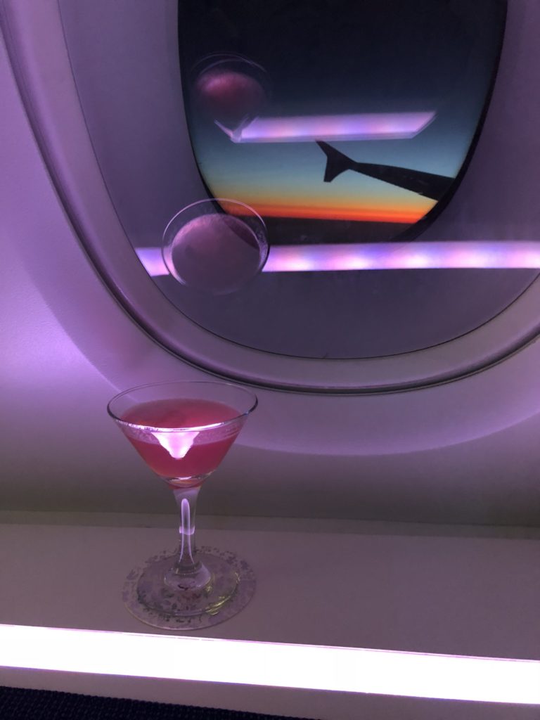 a glass of pink liquid in front of a window