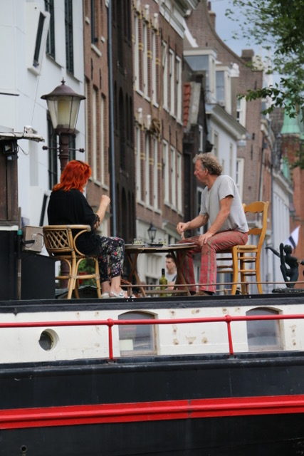 Friends enjoying a coffee alongside Amsterdam waterway
