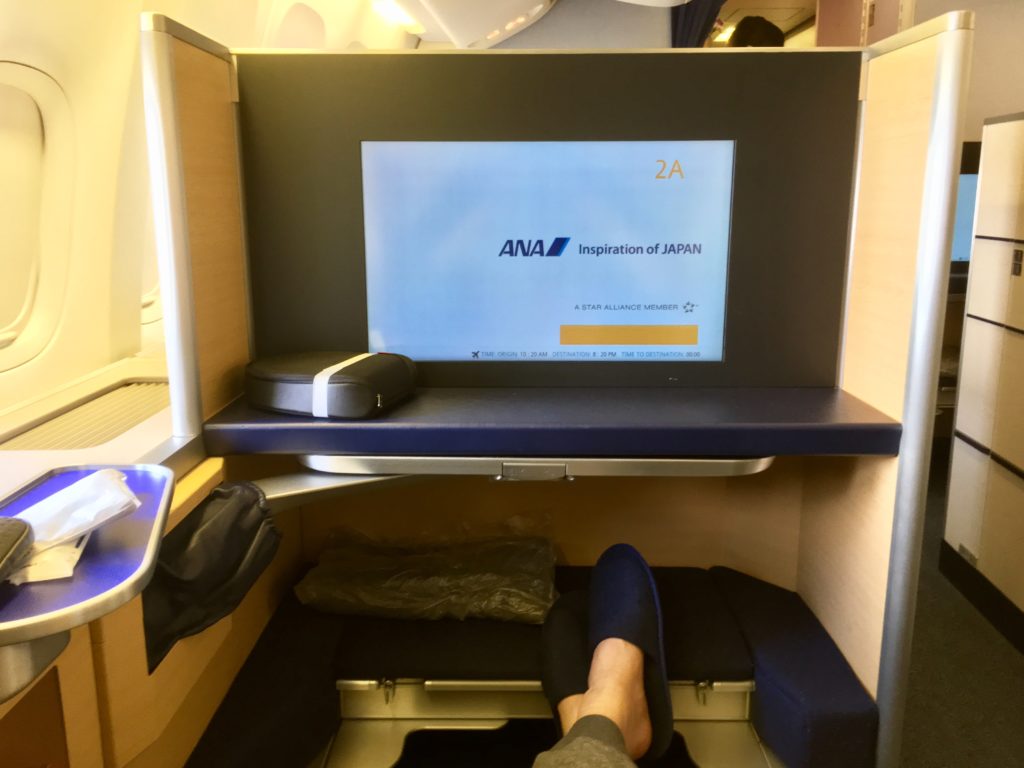 a person's feet in a chair with a screen on the back of a plane
