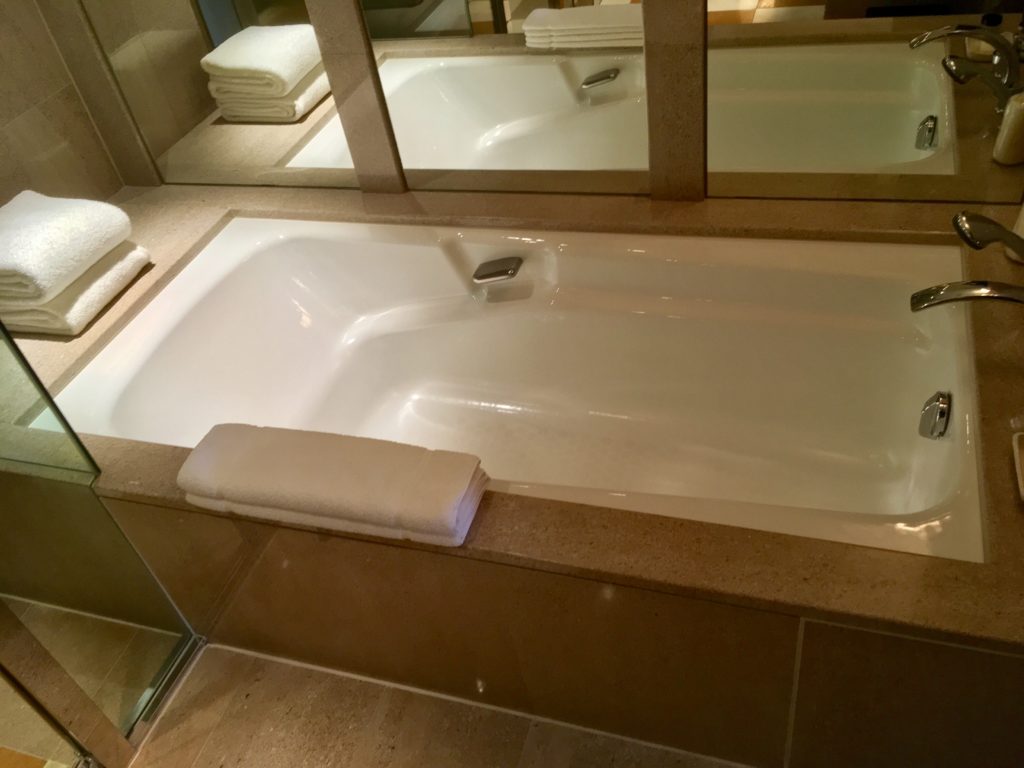 a bathtub with a mirror above it