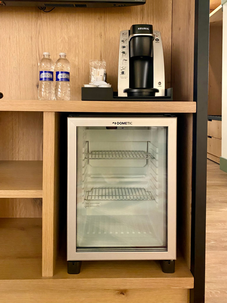 a small refrigerator with a coffee maker and bottles of water on a shelf
