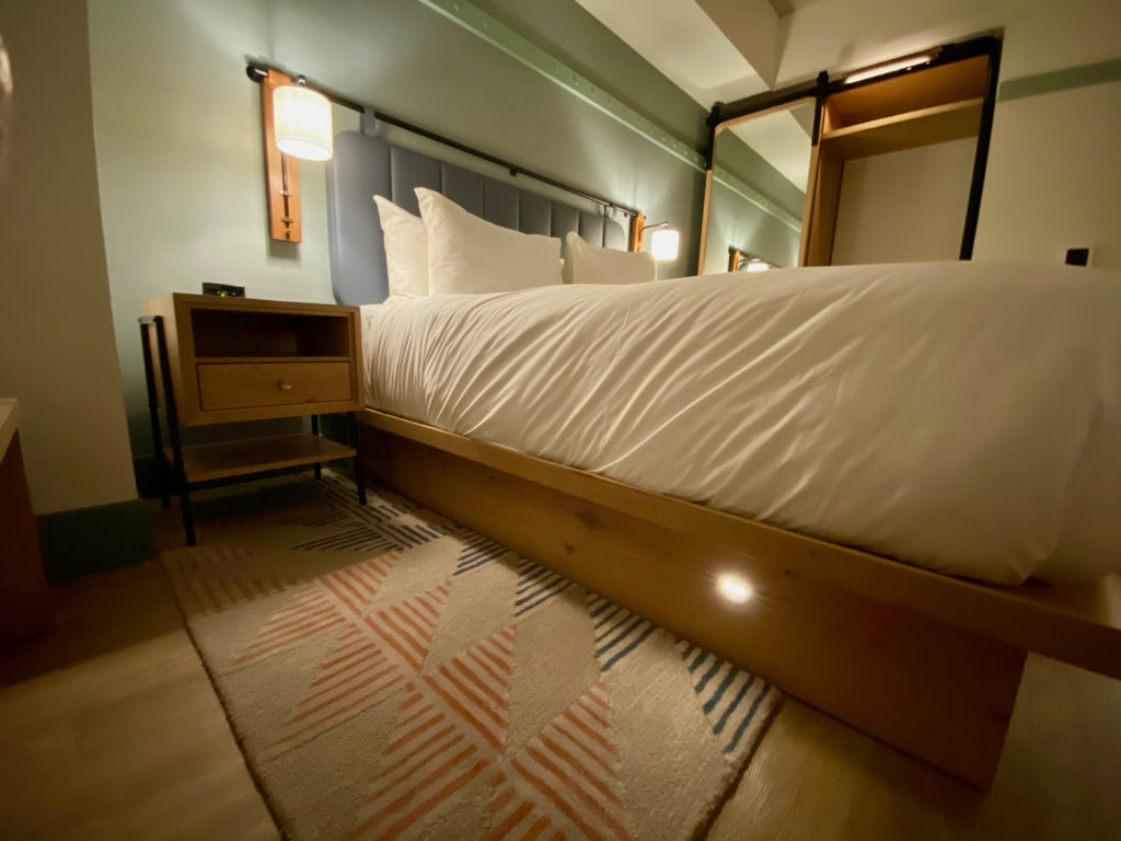 a bed with white sheets and a wood bed frame