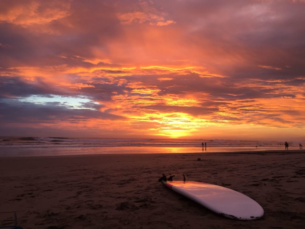 A surfboard on the beach against a lit up sky at Sunset in Samara Beach, Costa Rica