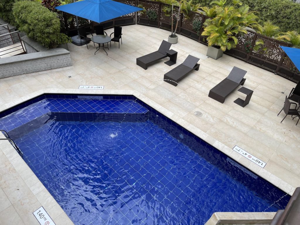 a pool with chairs and umbrella on a patio