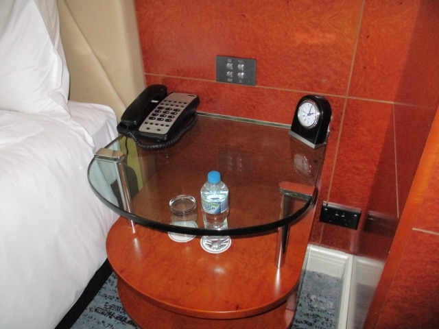 Park Hyatt Melbourne King Suite bedroom glass table with a phone and a bottle of water on it